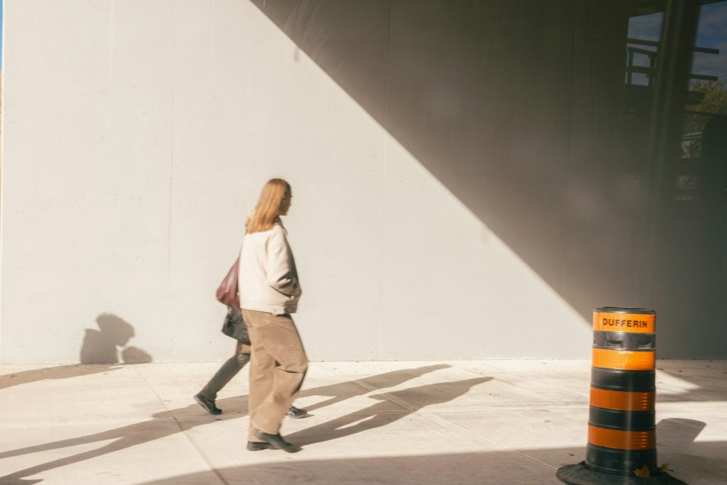 Two people walk past a construction cone.