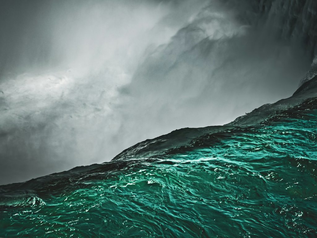 Turbulent green ocean waves under stormy grey clouds