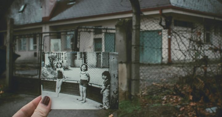 person holding photo of three girls near chainlink fence